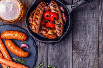 Grilled sausages with glass of beer on wooden table.