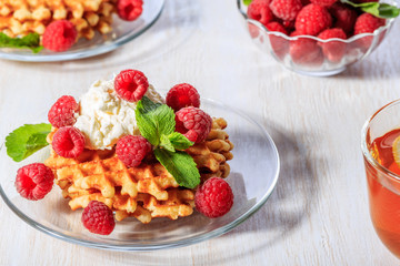 Waffles garnished with mascarpone and raspberries.