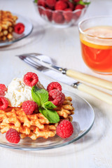 Waffles garnished with mascarpone and raspberries.
