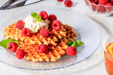 Waffles garnished with mascarpone and raspberries.