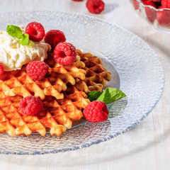 Waffles garnished with mascarpone and raspberries.
