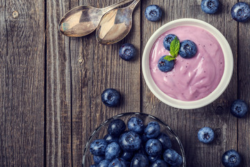 Homemade yogurt with fresh blueberry on a wooden background.