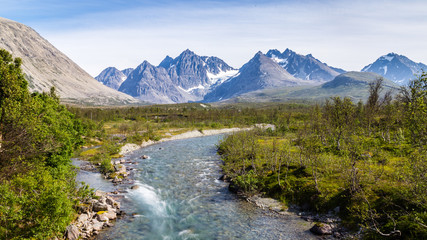 Naklejka na ściany i meble Scandinavian landscape with rapids in a river and a glacier in the background on the island Lyngen in Norway