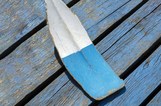 Old oar lying on a wooden platform.