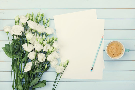 Fototapeta Morning coffee cup, empty paper list, pencil, and bouquet of white flowers eustoma on blue rustic table from above. Woman working desk. Cozy breakfast. Flat lay styling.