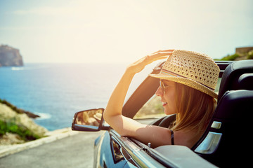 Side view on smiling woman in convertible car - obrazy, fototapety, plakaty