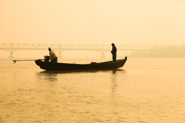 Fishing boat silhouette with Mawlamyine Thanlwin Bridge background.
