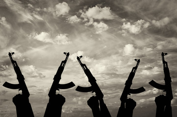 Silhouette of men hands holding rifle against cloudy sky
