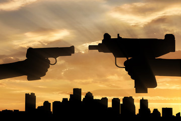 Silhouette of men hands holding gun during sunset