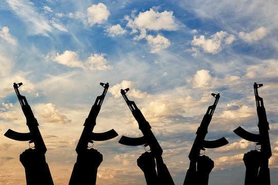 Silhouette of men hands holding rifle during sunset
