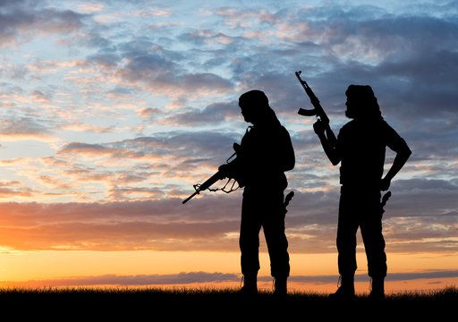 Silhouette of men with rifles during sunset