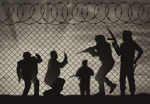 Silhouette of armed men attacking civilians near fence of barbed wire