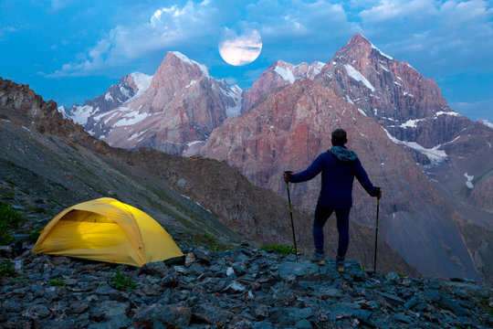 Silhouette of Hiker with illuminated tent and twilight Sky
