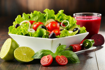 Composition with vegetable salad bowl and glass of juice