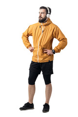 Confident young male in jogging sportswear wearing windbreaker jacket with hands on hips looking away. Full body length portrait isolated on white background.