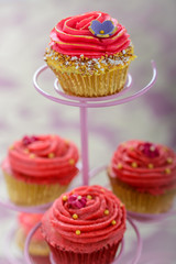 Selection of Bollywood style cupcakes on a cake stand decorated with pink piped icing, sugar flowers and yellow 