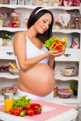 Obraz na płótnie Canvas Smiling pregnant woman with a plate of fresh vegetable salad. Pregnancy and healthy food