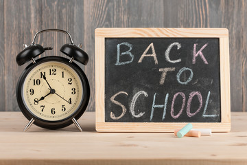 Back to school background with alarm clock and chalkboard
