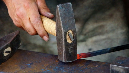 Schmied bearbeitet mit dem Hammer glühenden Stahl auf dem Amboss (Nahaufnahme)