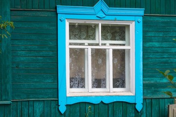 Blauer Fensterrahmen, grüne Holzwand