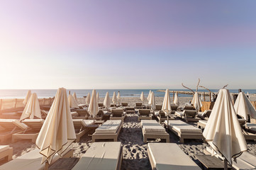 Obraz na płótnie Canvas Beach with chaise lounges, umbrellas, palm trees and the sea