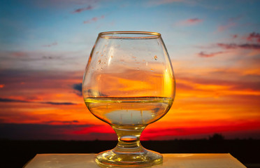 glass with water on sunset background