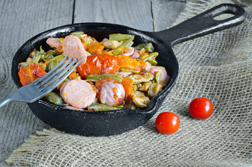 Roasted vegetables with sliced sausage.