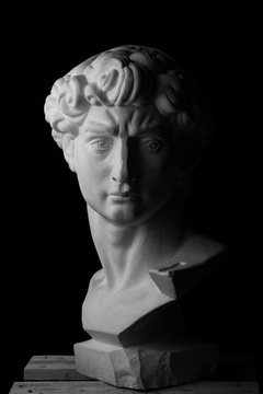 gypsum bust of David over a black background