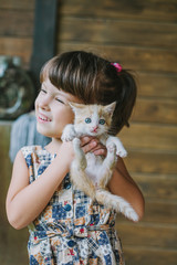 cheerful little girl holding a cat in her arms