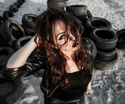 Redhead woman at the background of an old tires