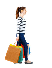 side view of going  woman  with shopping bags . beautiful girl in motion.  backside view of person.  Rear view people collection. Isolated over white background. Girl in a striped sweater comes with