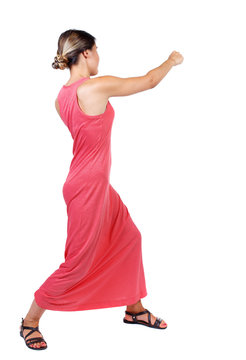 skinny woman funny fights waving his arms and legs. Isolated over white background. A slender woman in a long red dress punches.