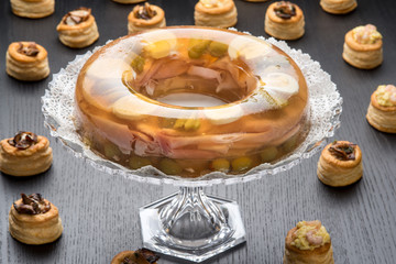 Alzatina di cristallo con aspic tra i vol-au-vent ripieni su un tavolo nero