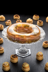 Alzatina di cristallo con aspic tra i vol-au-vent ripieni su un tavolo nero