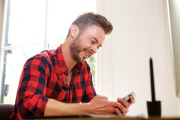 Fototapeta premium Smiling middle age man sitting at desk with cellphone