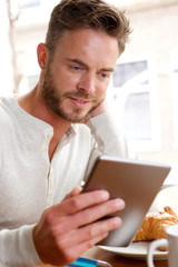 Handsome man looking at tablet over breakfast