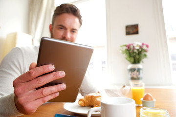 Older man holding tablet over breakfast