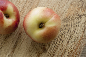 Peaches lie on weathered wooden surface