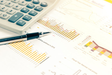 Obraz premium Close up of pen on financial documents with calculator in background. Business concept photo with sunlight filter.