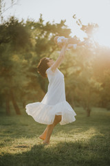 Happy young mother having fun, bowl, rising up, piggyback ride her child in park on summer sunset	