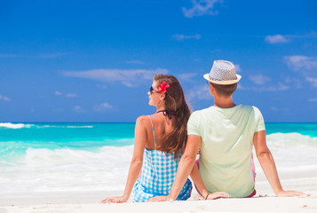 Romantic couple in bright clothes enjoying sunny day at tropical beach