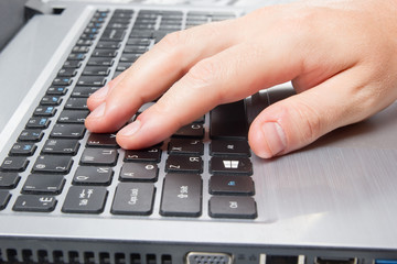 Man's hands typing laptop keyboard making online payment at home against the wooden table. On-line...