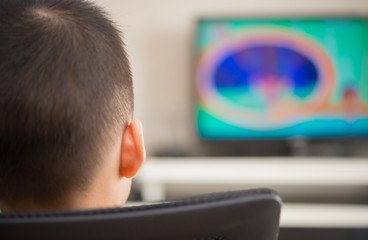 kid sitting and watching television broadcasting cartoon at home