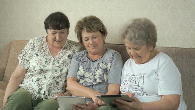 Elderly women looking photos using digital tablets