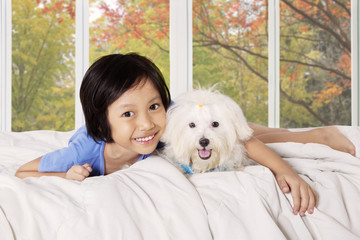 Girl hugging her puppy on the bed