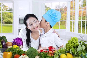 Little boy kiss his mother in the kitchen