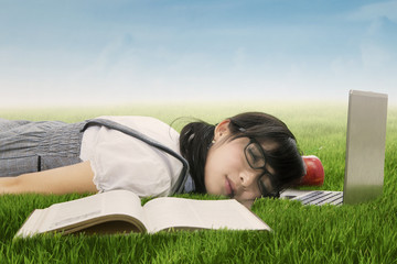 Student sleeping on laptop at grass