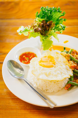Thai pork spicy food eat with rice and fried egg on wood table.