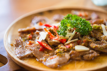 Pork Stir-fly with Spicy Garlic served on wood table, Thai Herbal Food Meal Concept.