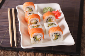 Philadelphia sushi roll with salmon served with wasabi and ginger close-up. Horizontal
